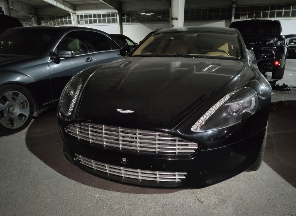 Black Aston Martin in a parking garage.