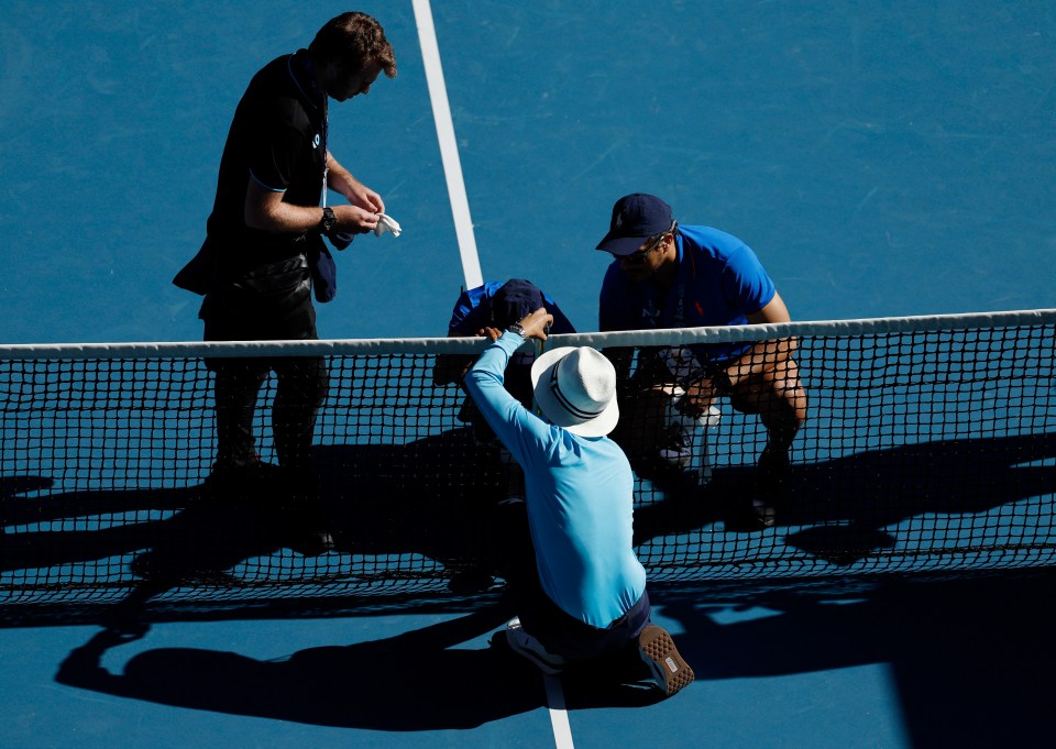 Tennis officials adjusting the net.