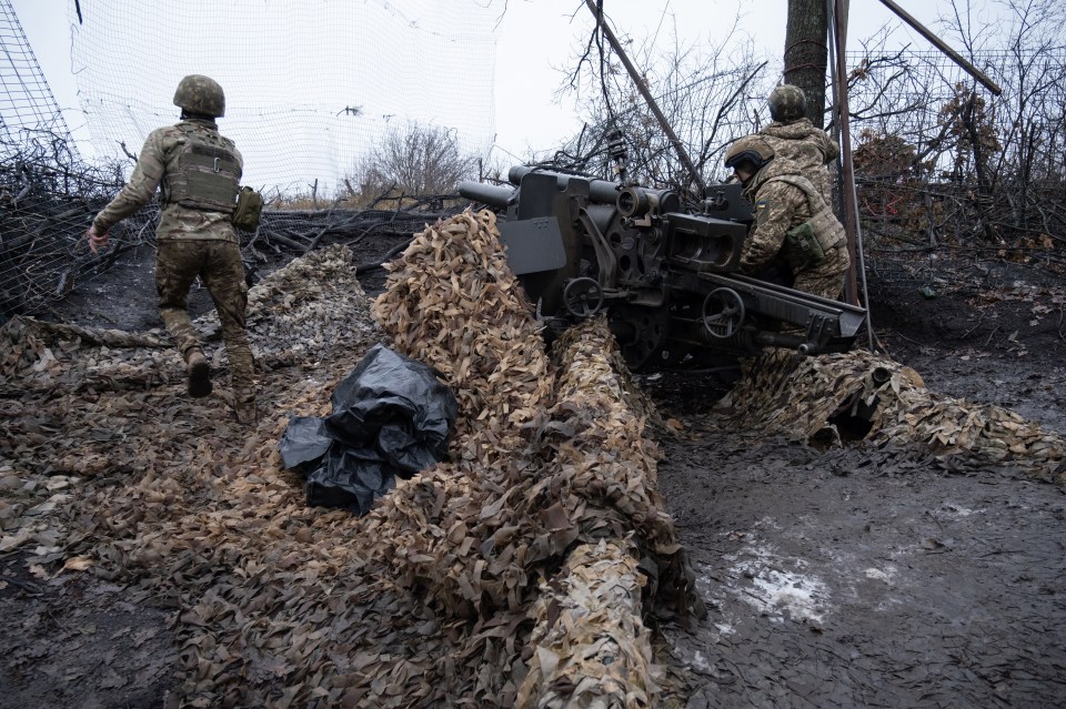 Ukrainian soldiers operating a camouflaged US-made M101A1 howitzer.