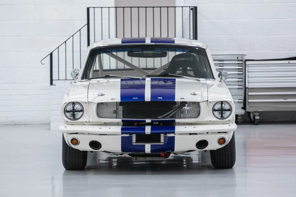 Front view of a white 1966 Ford Mustang with blue racing stripes.