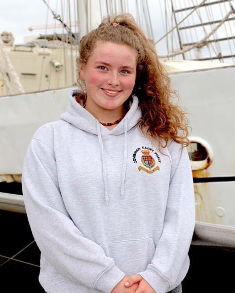 Young woman in Combined Cadet Force hoodie in front of a ship.