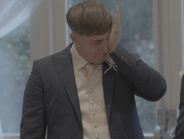 A groom wiping away tears at a wedding.