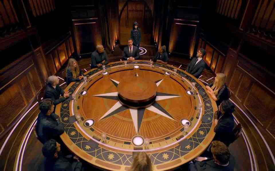 The Traitors contestants seated around a large round table.