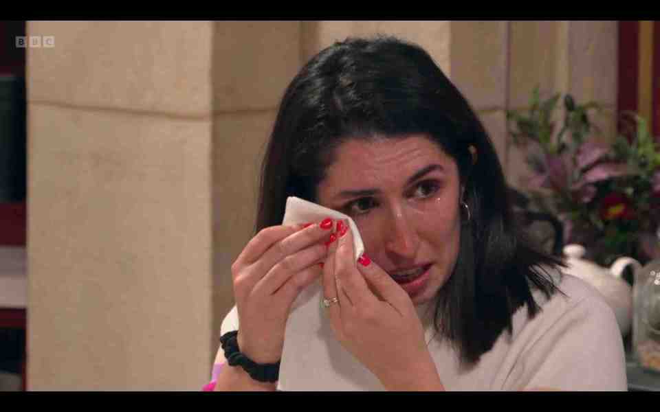 A woman crying and wiping her tears with a tissue.