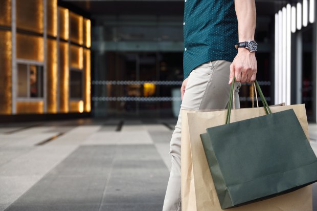 Man carrying shopping bags outside a luxury mall.