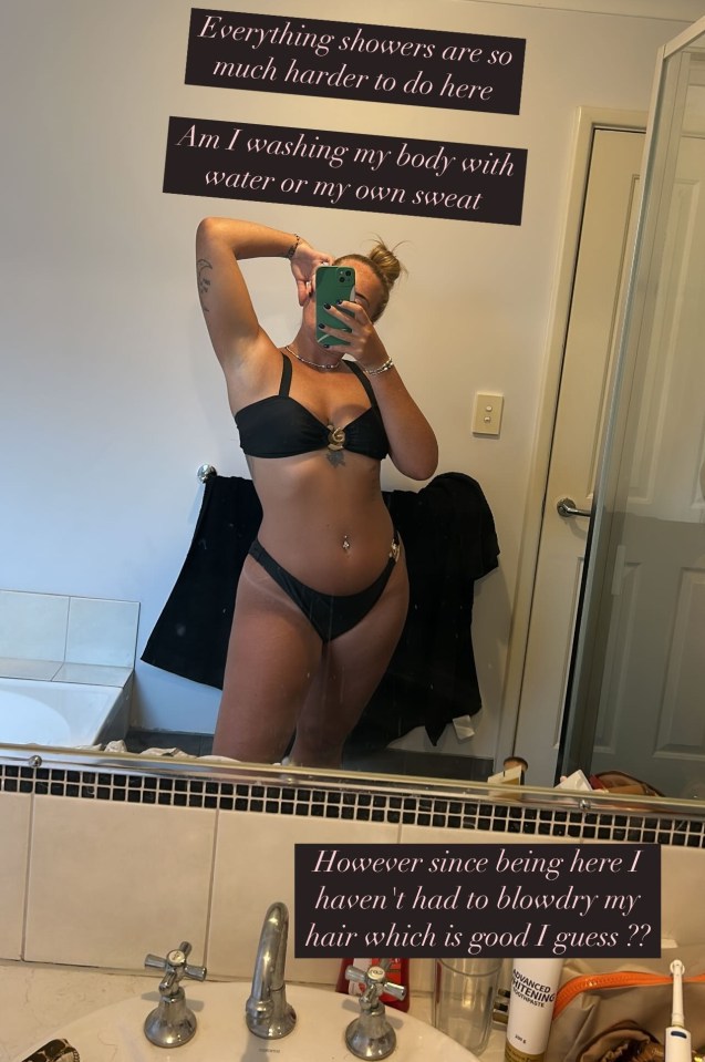 Woman in a black bikini in a bathroom mirror, commenting on the difficulty of showering.