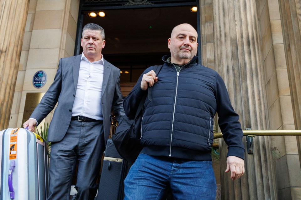 Two men with luggage outside a hotel.