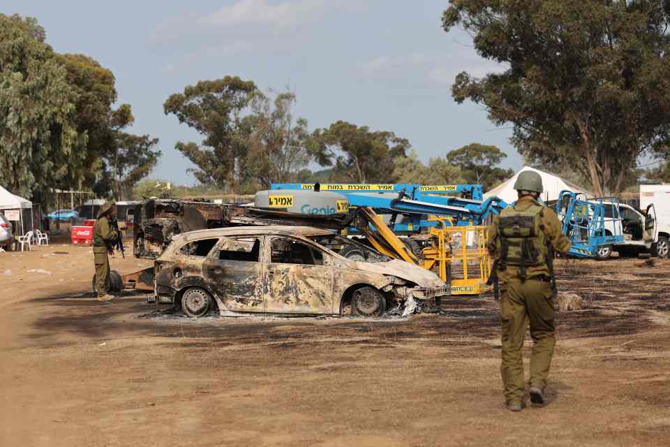 Burned cars and a soldier at the site of a music festival attack.