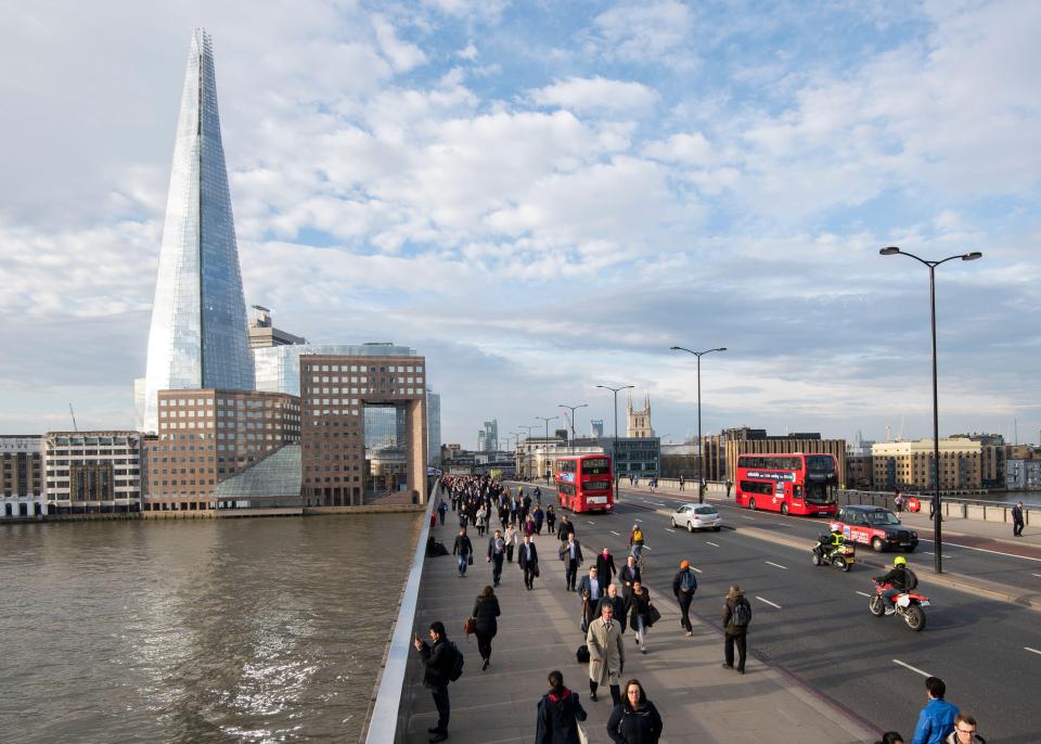 Elevated view of London Bridge with commuters, buses, and The Shard in the distance.