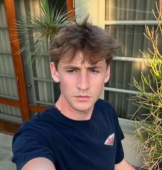 Selfie of a young man outside a house.