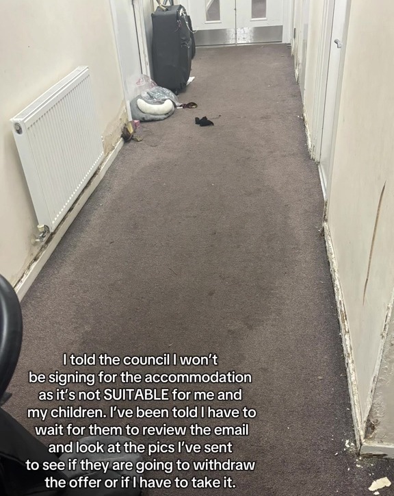 Photo of a dirty hallway with a suitcase and other belongings, showing unsuitable housing.