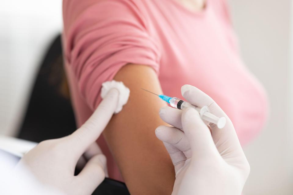 A doctor vaccinating a young woman.