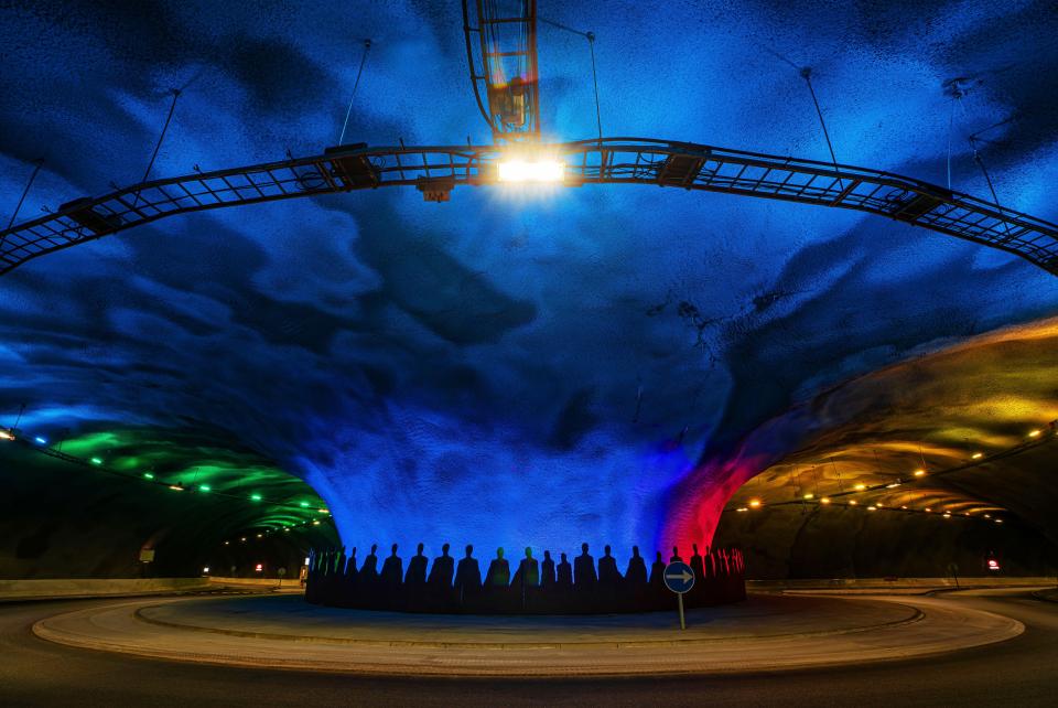 Streymoy-Eysturoy underwater tunnel in the Faroe Islands, illuminated with colorful lights and featuring silhouettes of people.