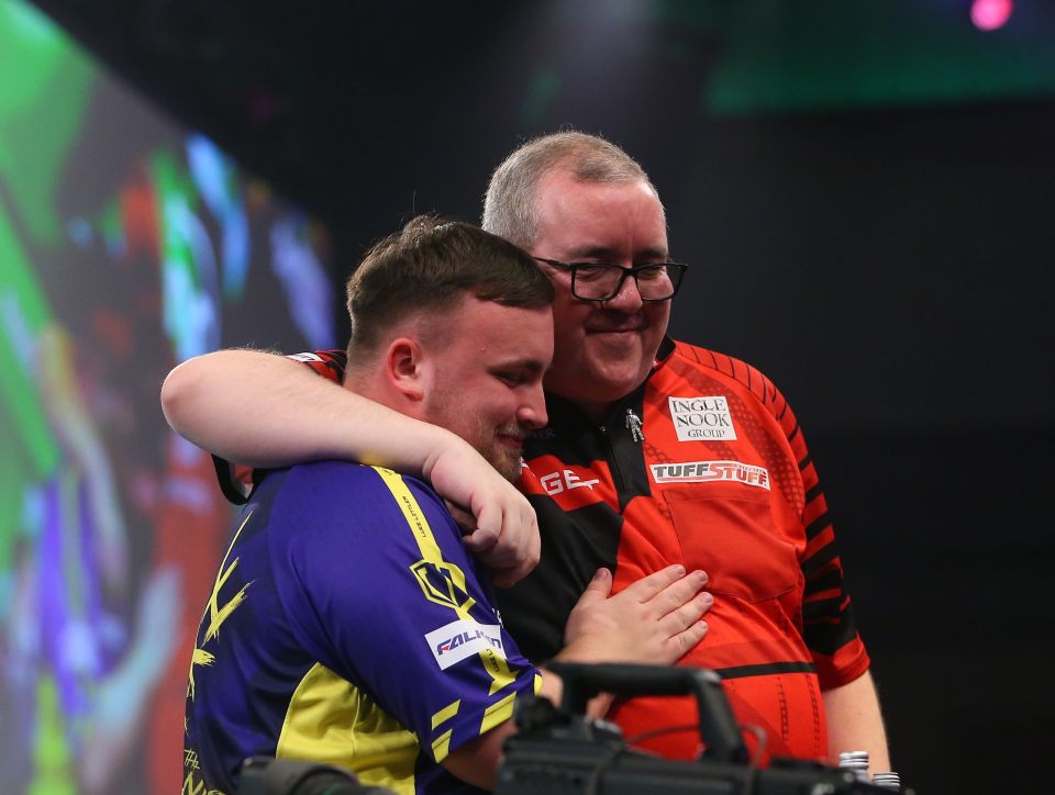 Luke Littler and Stephen Bunting embracing after a darts match.