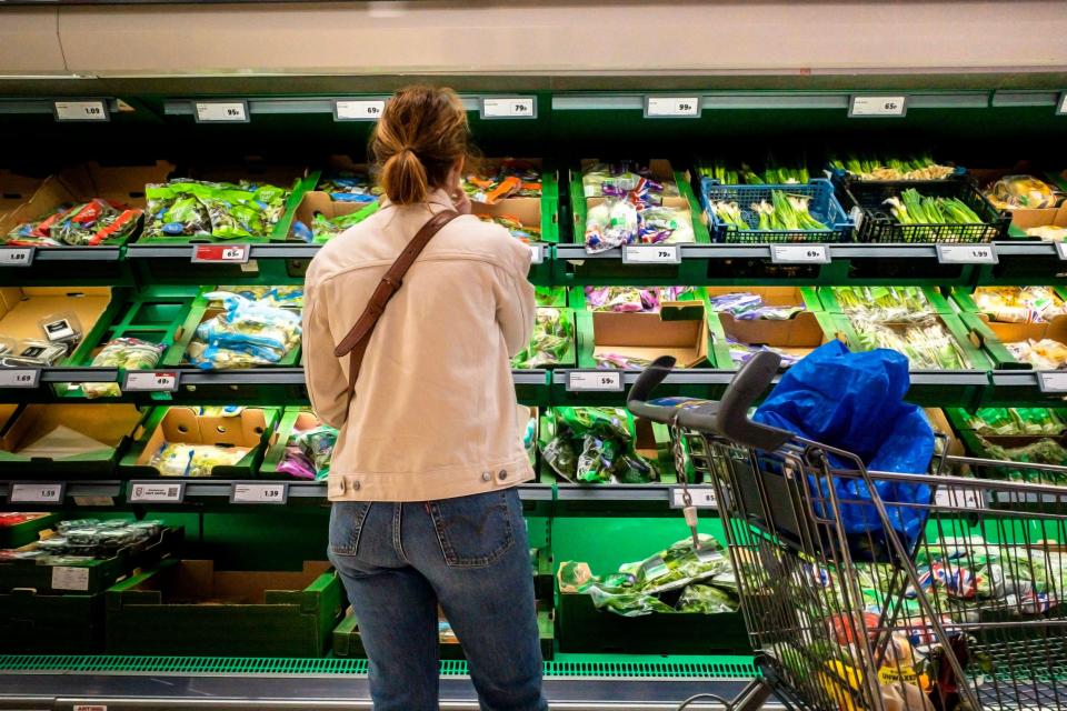 Shopper selecting fresh vegetables in a supermarket.