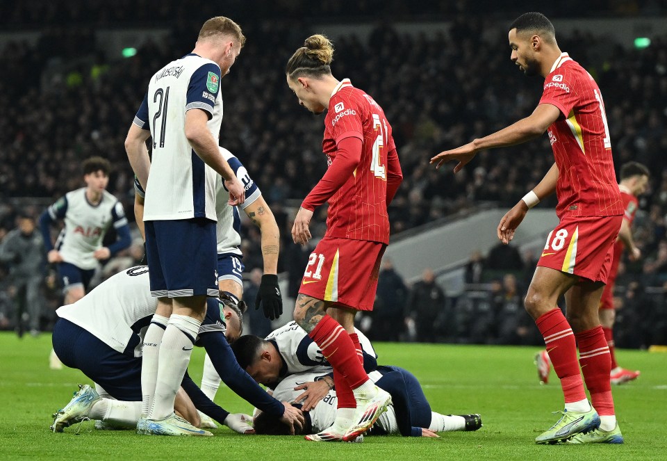 Injured Tottenham Hotspur player Rodrigo Bentancur on the ground surrounded by other players.