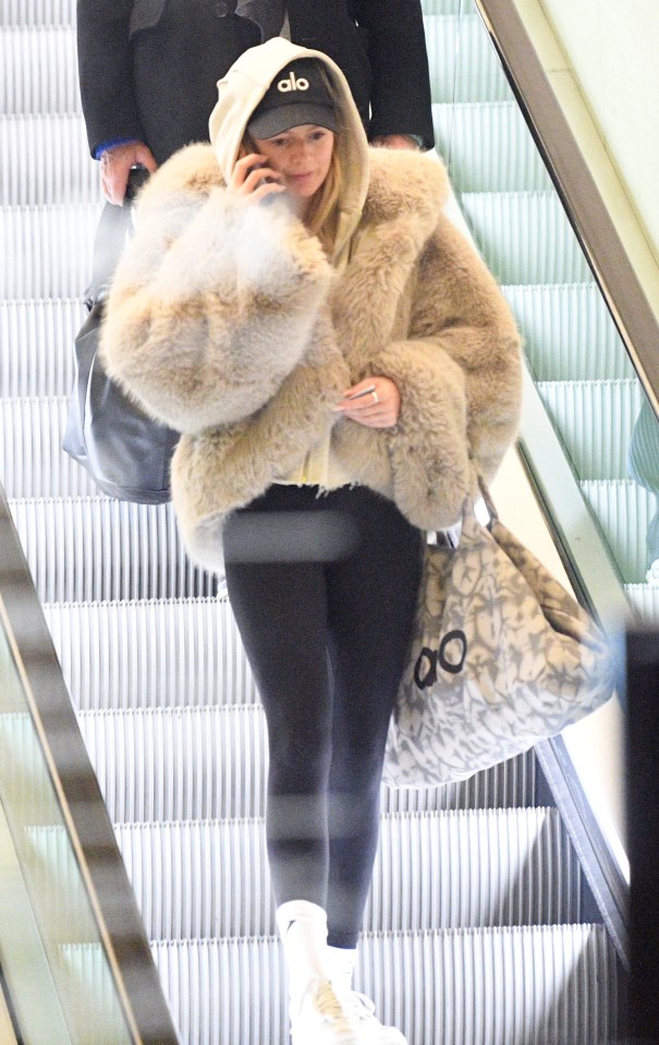 Tasha Ghouri on a phone call on an escalator.