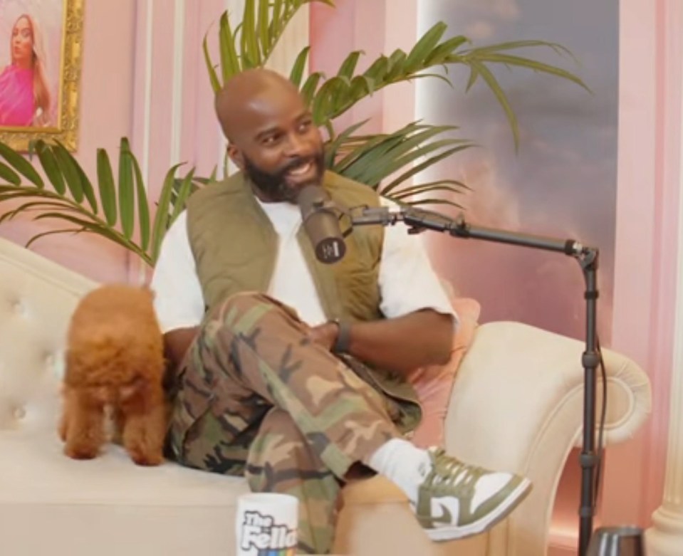 Melvin Odoom on a podcast, with a small dog.