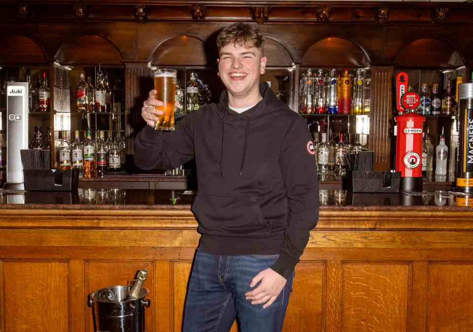 Lottery winner celebrating with a beer at a bar.