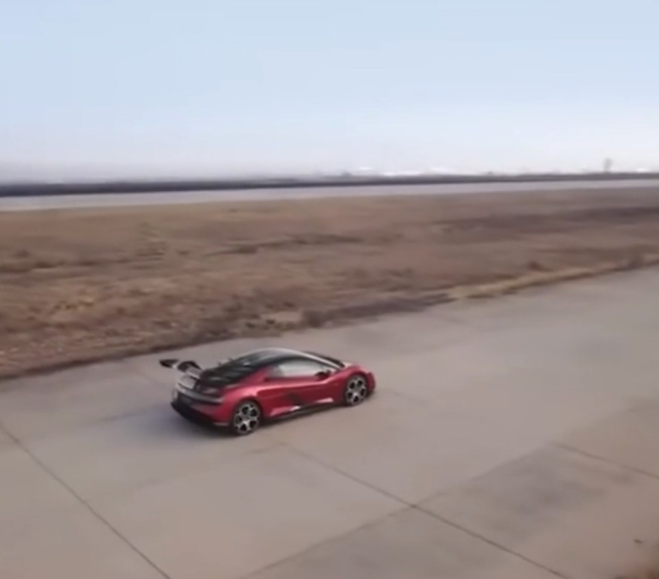 Red Yangwang U9 sports supercar driving on a road.