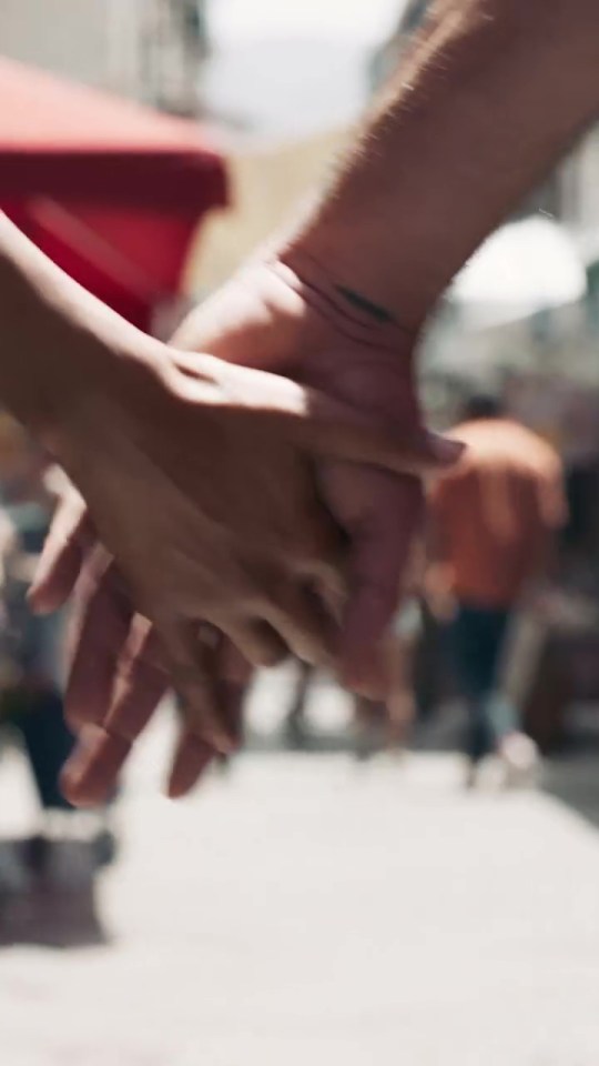 Close-up of two people holding hands.