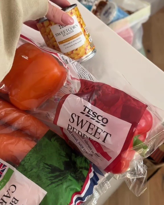 Groceries including sweetcorn, peppers, and carrots.