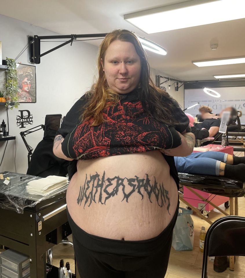 Woman showing off her large Wetherspoon's tattoo.