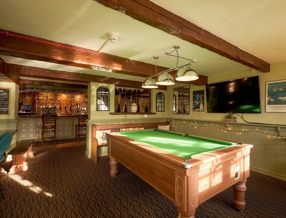 Interior of a pub with a pool table, bar, and flat-screen TV.