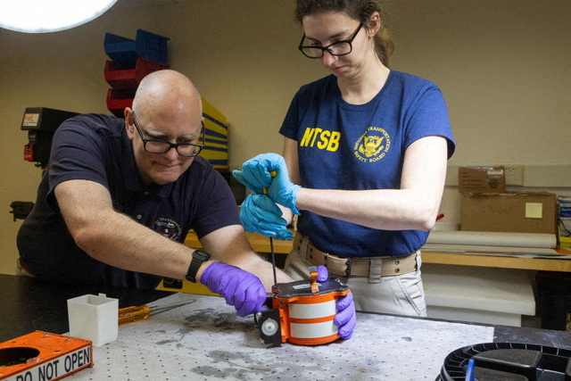 NTSB investigators examining a flight data recorder.