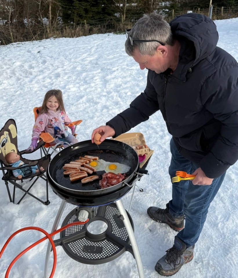 Man cooking breakfast outdoors in the snow.