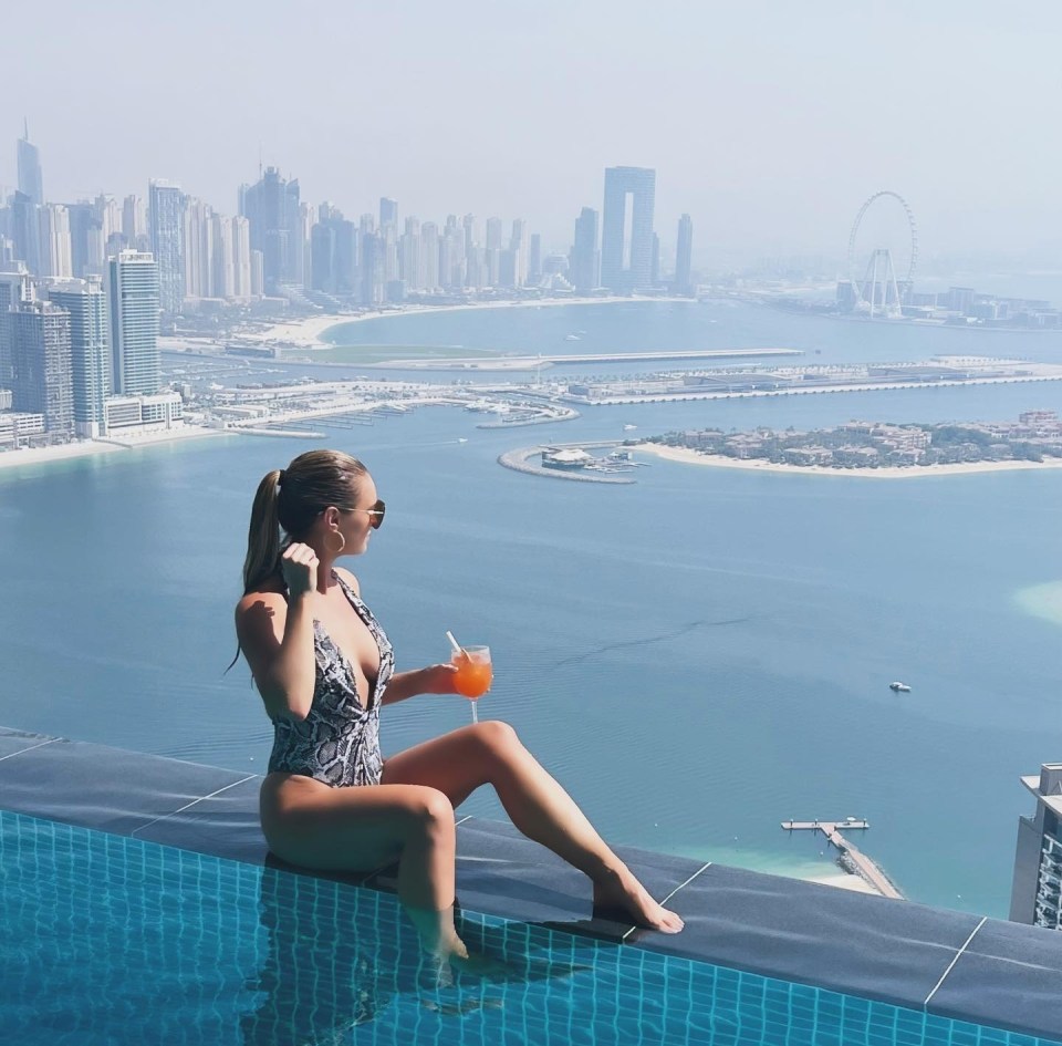 Woman in swimsuit relaxing in infinity pool overlooking Dubai skyline.