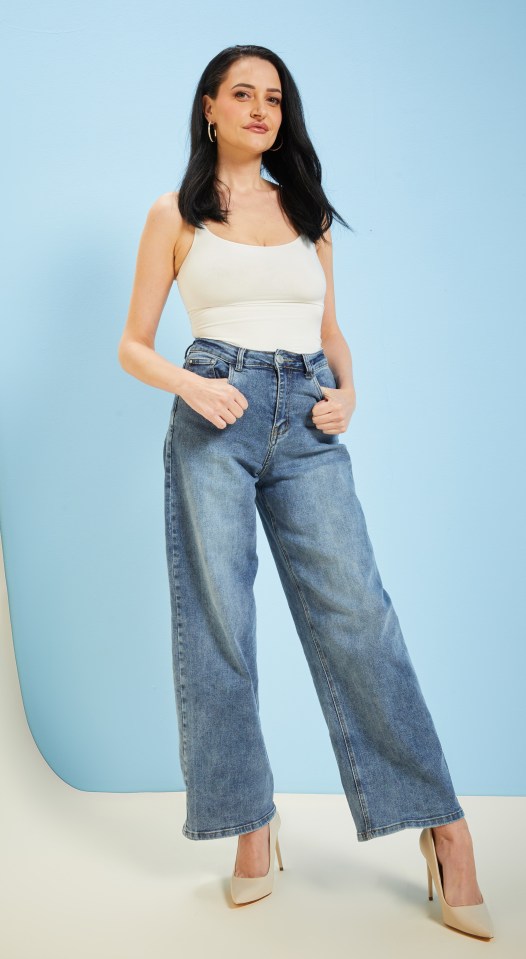 Woman in white tank top and wide-leg jeans.