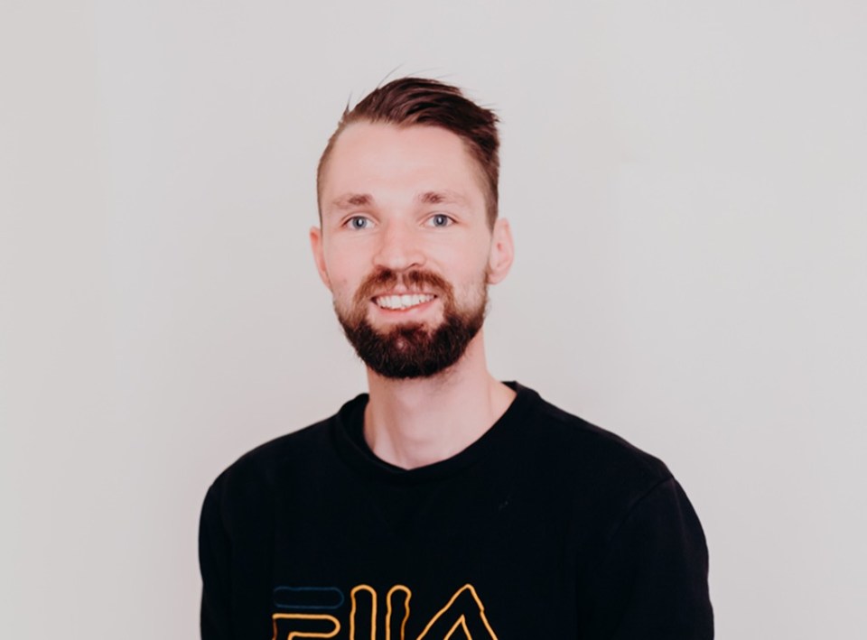 Portrait of a smiling man wearing a black sweatshirt.