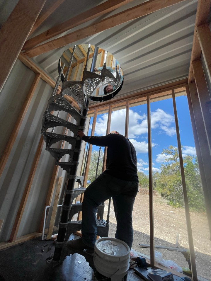 Person installing a spiral staircase in a shipping container home.