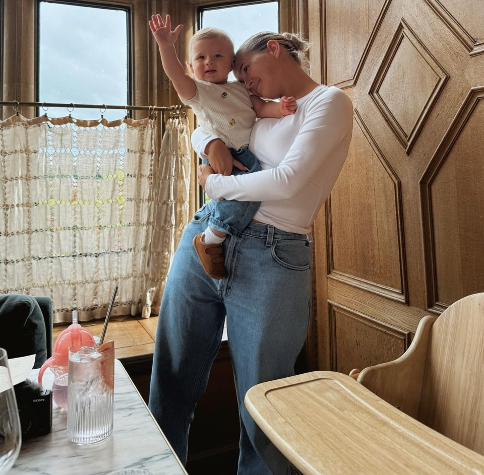 Woman holding baby in her arms near a window.