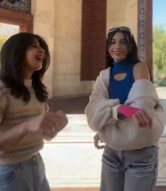 Two young women laughing together outdoors.