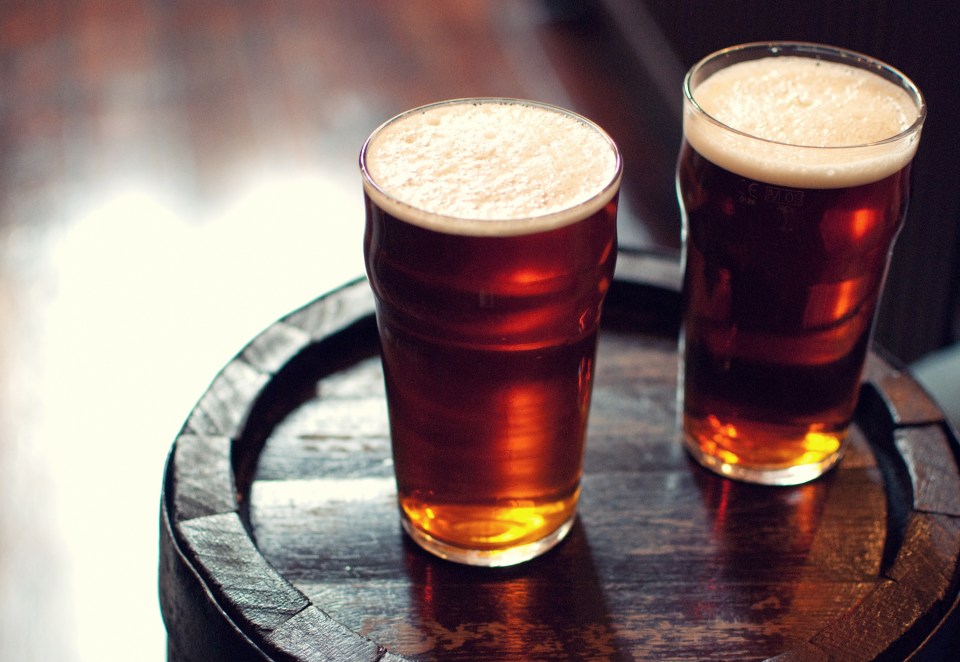 Two pints of bitter ale on a wooden barrel.