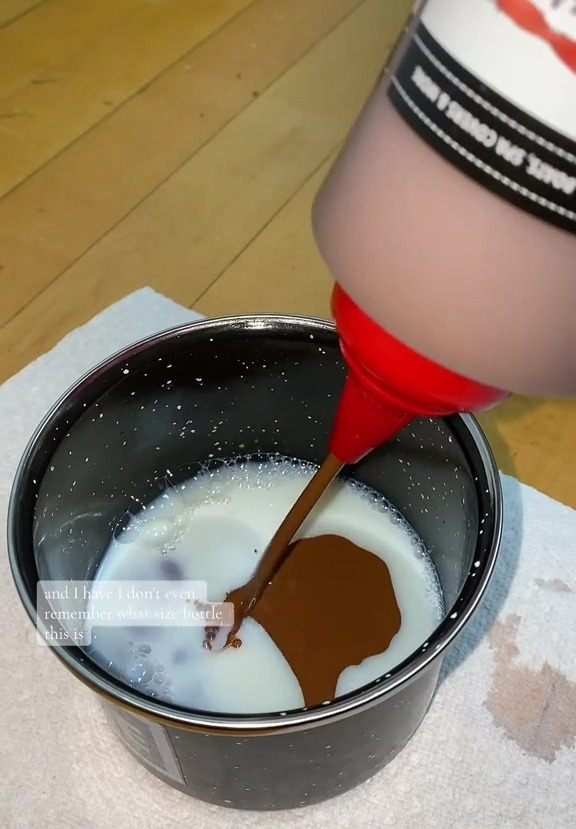 Brown liquid being poured into a bowl of milk.