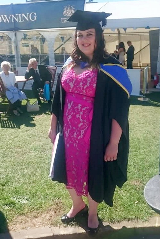 Woman in graduation gown and pink dress.