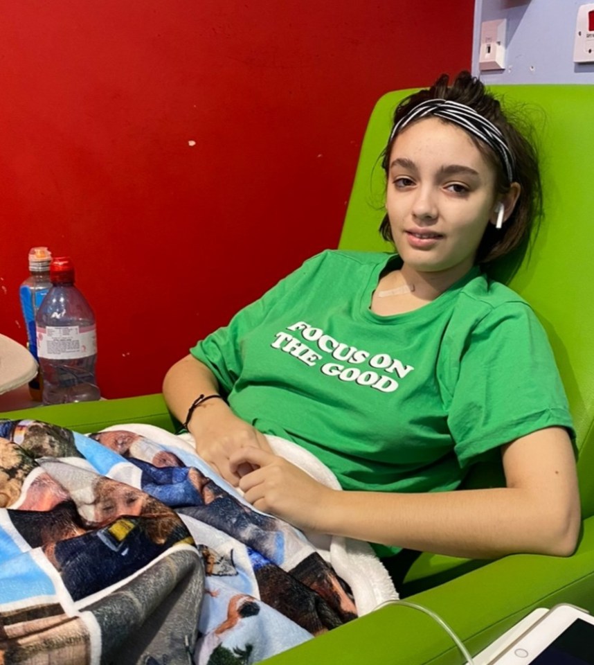 Teenage girl in a green chair receiving medical treatment.