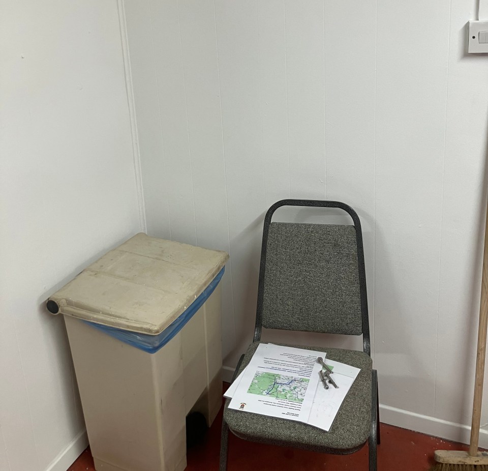 A chair with papers and bolts on it, next to a waste bin in a room.