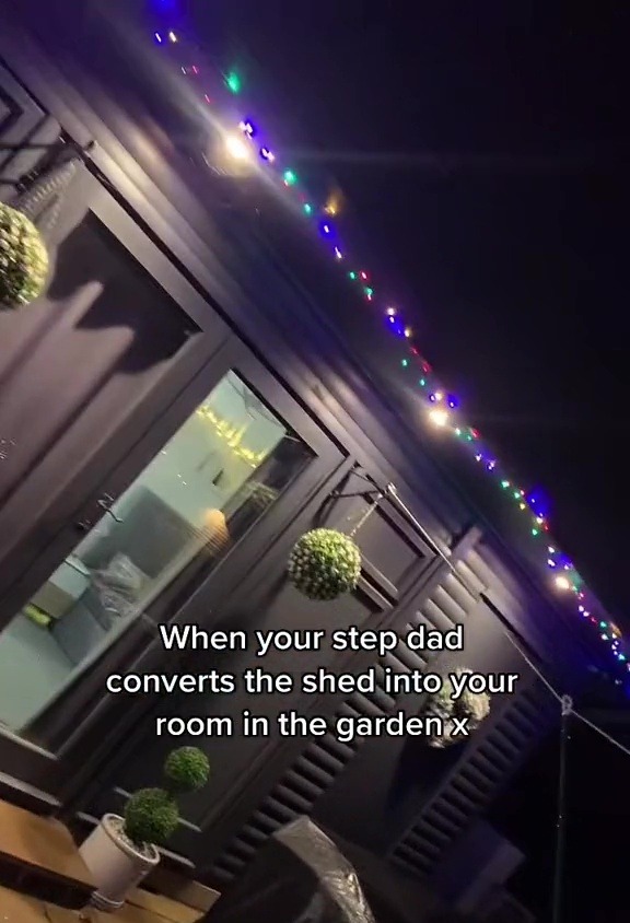 Nighttime view of a shed converted into a garden room, decorated with string lights.