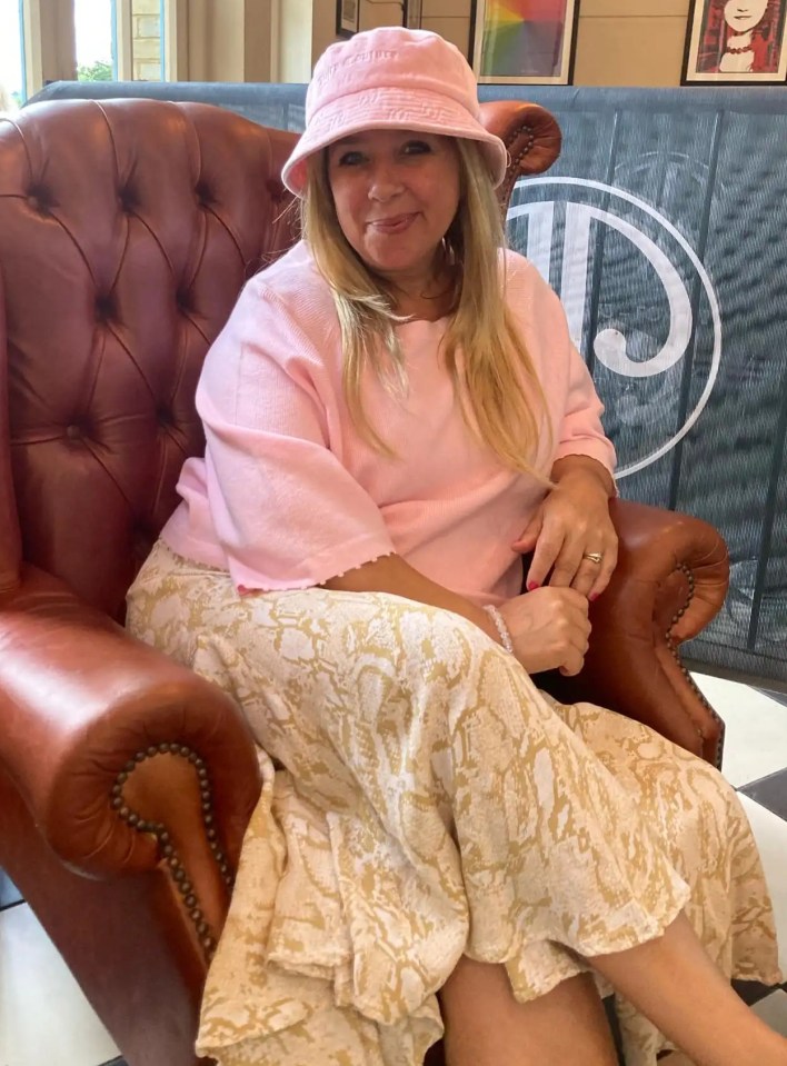 Woman in pink top and bucket hat sitting in a leather armchair.