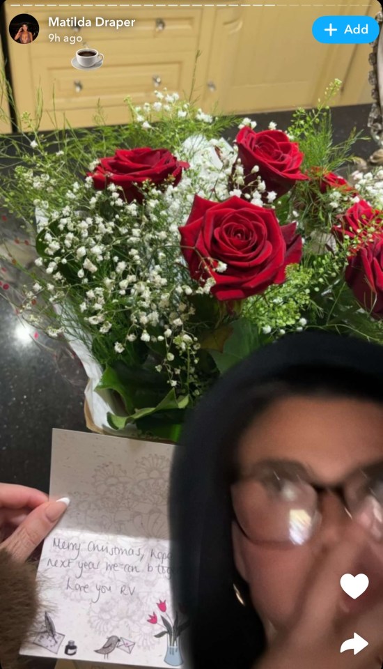 A woman shows a bouquet of red roses and a Christmas card.