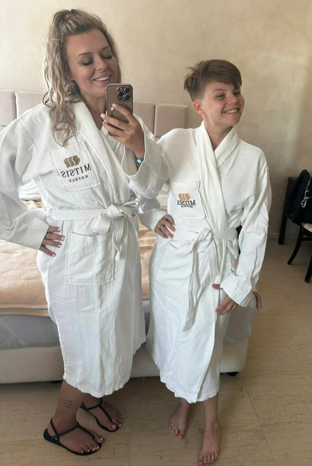 Two women in white bathrobes in a hotel room.