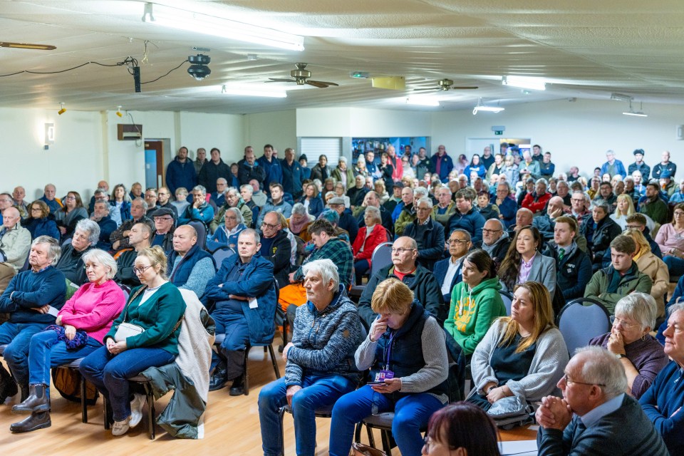 A large crowd of people at a public meeting.