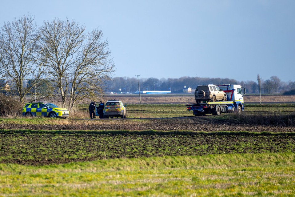 Police towing a vehicle away in a field.