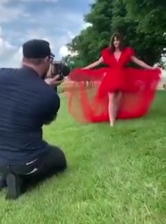 A photographer taking a picture of a model in a red dress.