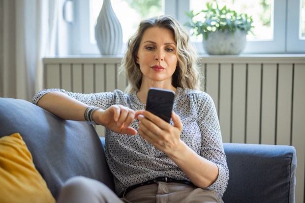 Woman using smartphone while sitting on a couch.