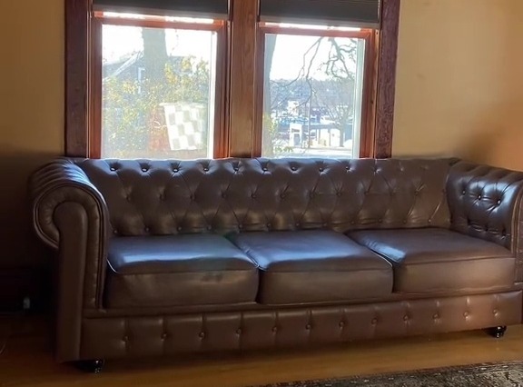 Restored brown leather sofa in front of a window.